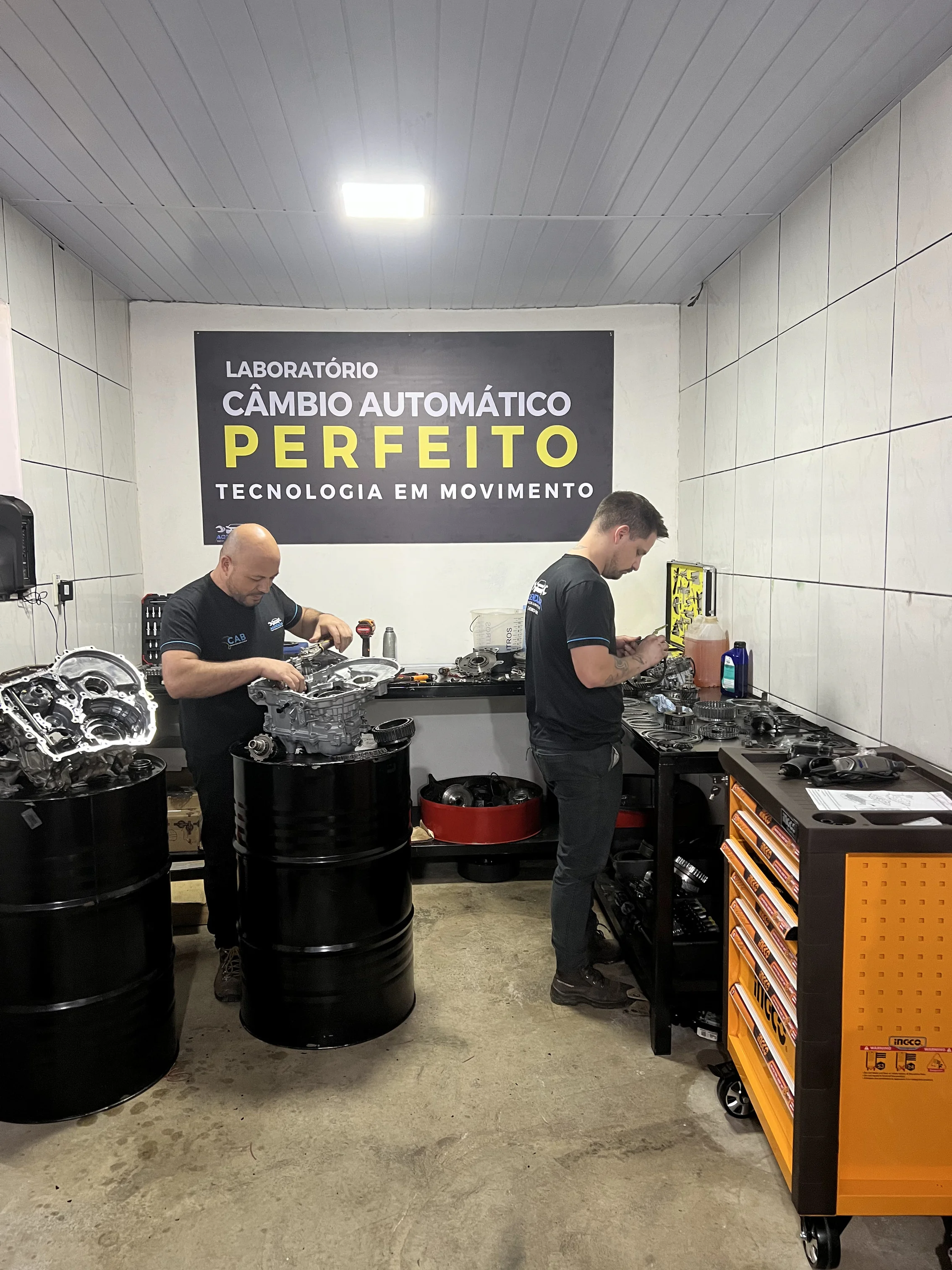 Dois técnicos da AgendaCar trabalhando juntos na remontagem de um câmbio automático